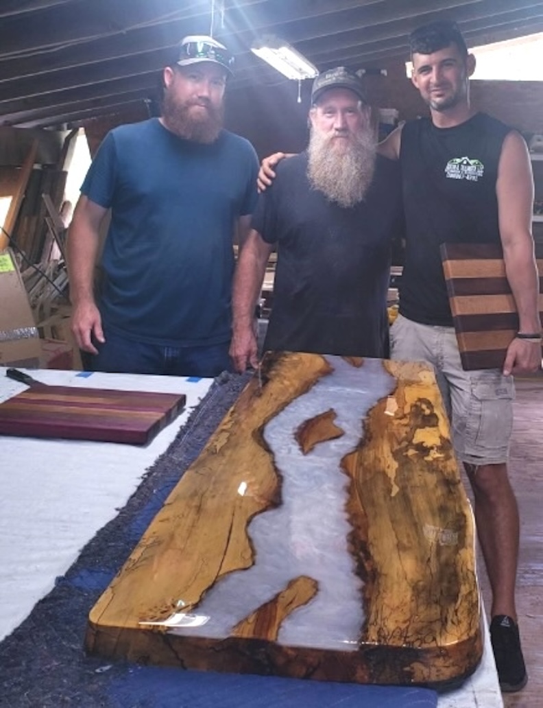 The Brennans present a handsome 'river table' to a happy customer. Chris (left) and Floyd (center) have created a thriving woodworking business with Woodmaster and TimberKing equipment.